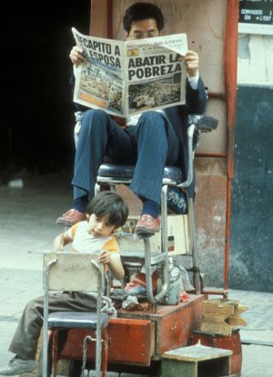 A child is cleaning the shoes of a mexican businessmen, which is reading in the newspaper all about the poverty in MexicoEin mexikanische Geschäftsmann lässt sich von einen Kind die Schuhe putzen und liest in der Zeitung über die Armut in Mexico.