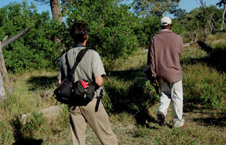 Der Zürcher Fotojournalist Gerd Müller bei seiner Lieblingsbeschäftigung: Bushwalk mit dem Bushmen in der Central-Kalahari. The Swiss Photojournalist Gerd Müller with a bushmen walking through the central Kalahari